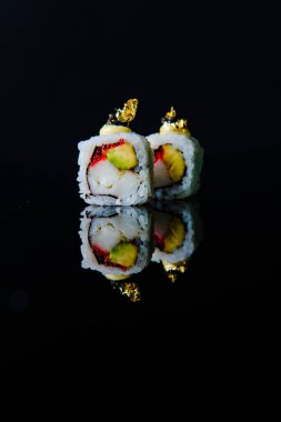 Somonlu suşi ve siyah arka planda salatalık.