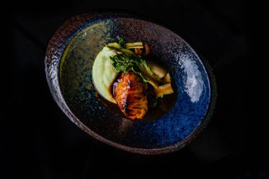 Siyah tabakta sebzeli ızgara somon bifteği.