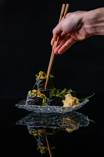 Masakan Jepang Sushi Dengan Sumpit Dan Tangan Latar Belakang Hitam — Stok Foto