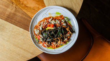 Yuvarlak tabakta erişte ve sebzeli gurme Asya yemeği manzarası.