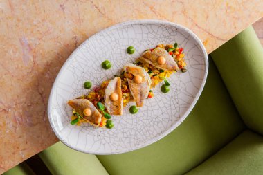 Beyaz tabakta kızarmış balık ve sebzeli Asya usulü aperatif.