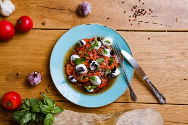 En üst tabakta lezzetli domates, mozarella ve fesleğen salatası var. 