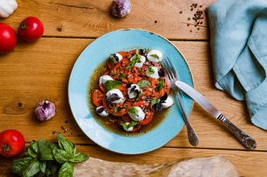 En üst tabakta lezzetli domates, mozarella ve fesleğen salatası var. 