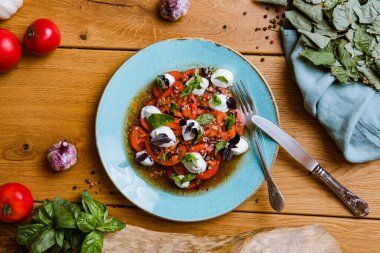En üst tabakta lezzetli domates, mozarella ve fesleğen salatası var. 