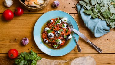 Lezzetli domates, mozarella ve ahşap masada fesleğen salatası. 