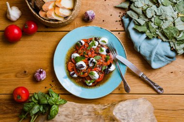 Lezzetli domates, mozarella ve ahşap masada fesleğen salatası.