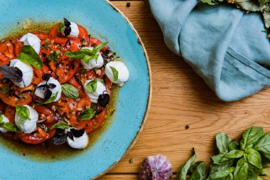 Lezzetli domates, mozarella ve ahşap masada fesleğen salatası.