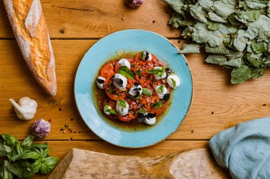 Lezzetli domates, mozarella ve ahşap masada fesleğen salatası manzarası.
