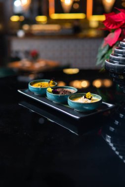 Lokantadaki siyah masada yenebilir çiçeklerle dolu gurme yemeklere yakın çekim, seçici odaklanma.