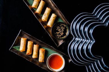 Siyah arka planda soslu lezzetli doldurulmuş ruloların üst görüntüsü.