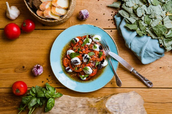 Lezzetli domates, mozarella ve ahşap masada fesleğen salatası.