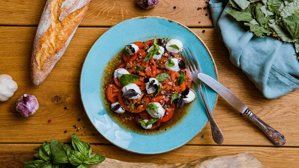 Lezzetli domates, mozarella ve ahşap masada fesleğen salatası.