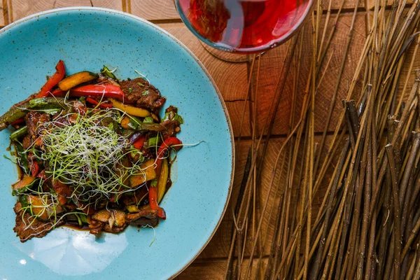 Kızarmış et, sebze, şifalı ot ve bir bardak kırmızı şarap ile nefis bir yemek manzarası.