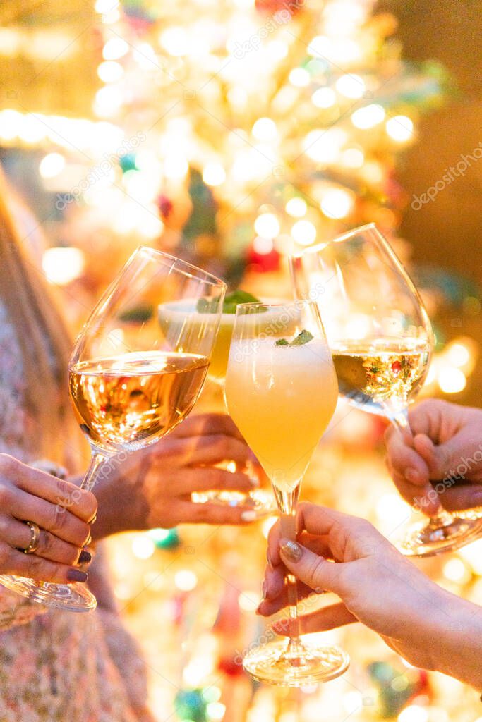 cropped shot of people clinking glasses with drinks at christmas party