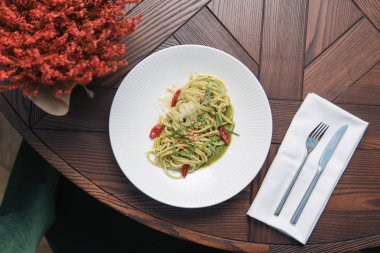 Pesto soslu spagetti ve parmesan peyniri restorandaki masada.