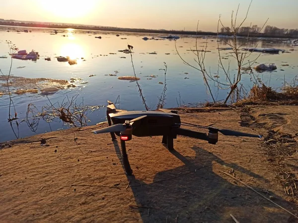 Quadcopter gün batımında nehrin üzerinde uçuyor.