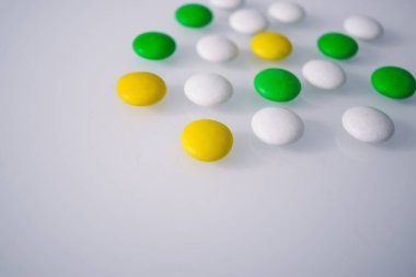 Tabletler ya da şekerler, beyaz ve renkli bir masada. 