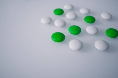 Tabletler ya da şekerler, beyaz ve renkli bir masada. 