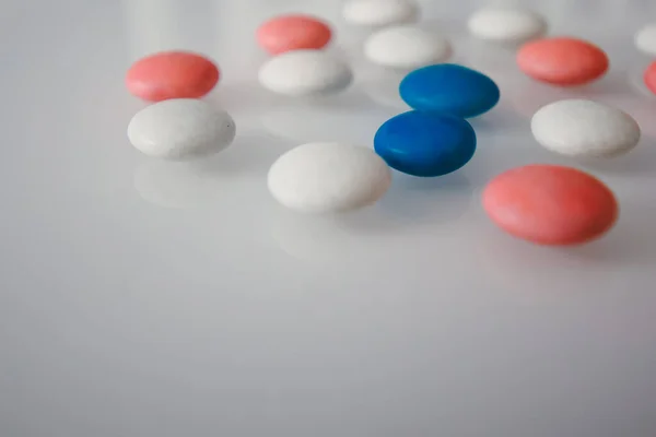 tablets or candies, white and colored on a white table