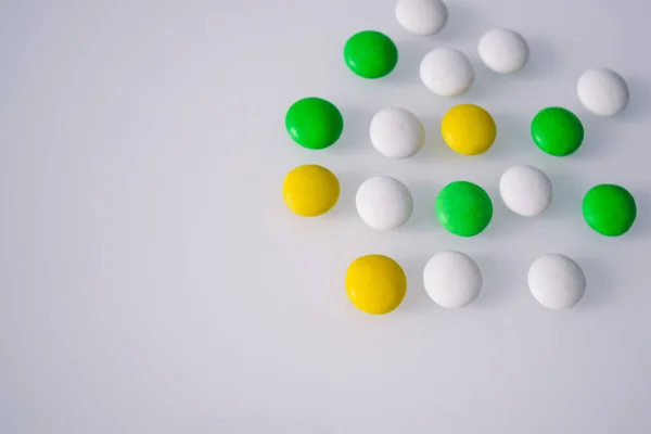 tablets or candies, white and colored on a white table