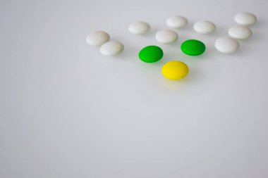 Tabletler ya da şekerler, beyaz ve renkli bir masada. 