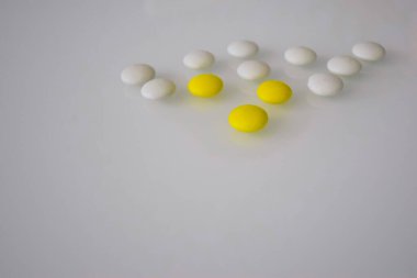 Tabletler ya da şekerler, beyaz ve renkli bir masada. 