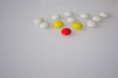 Tabletler ya da şekerler, beyaz ve renkli bir masada. 