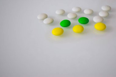 Tabletler ya da şekerler, beyaz ve renkli bir masada. 