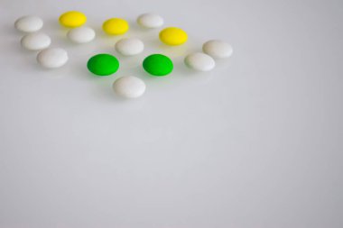 Tabletler ya da şekerler, beyaz ve renkli bir masada. 