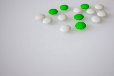 Tabletler ya da şekerler, beyaz ve renkli bir masada. 