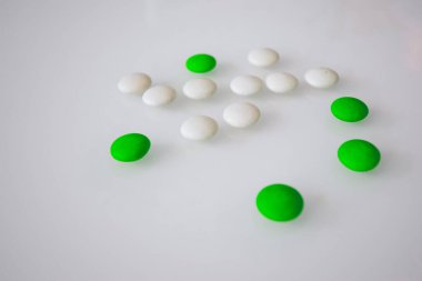 Tabletler ya da şekerler, beyaz ve renkli bir masada. 