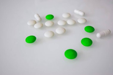 Tabletler ya da şekerler, beyaz ve renkli bir masada. 