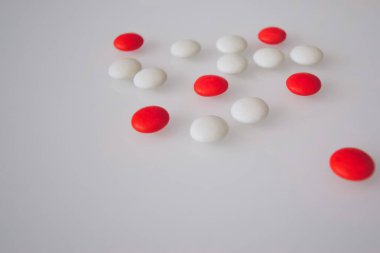 Tabletler ya da şekerler, beyaz ve renkli bir masada. 