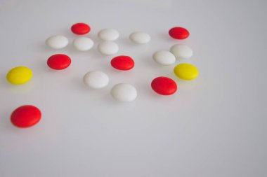 Tabletler ya da şekerler, beyaz ve renkli bir masada. 