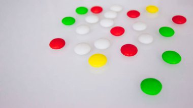 Tabletler ya da şekerler, beyaz ve renkli bir masada. 