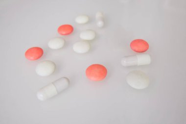 Tabletler ya da şekerler, beyaz ve renkli bir masada. 