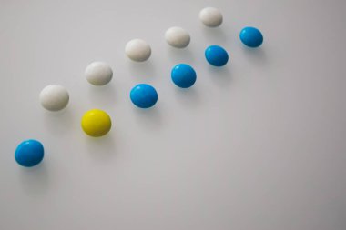 Tabletler ya da şekerler, beyaz ve renkli bir masada. 