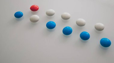 Tabletler ya da şekerler, beyaz ve renkli bir masada. 