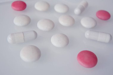 Beyaz cam bir masada farklı renkte haplar veya şekerler. 