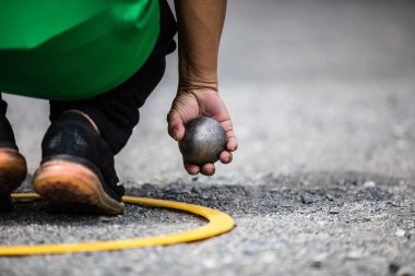 Petanque Ball veya Boule 'a el ele tutuşun. Sarı daire konumundaki adam.