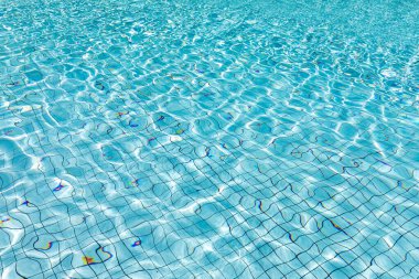 Yüzme havuzunun berrak ve parlak mavi sularında güneş yansıması, parlak mavi su dalgalanması arka plan, su dokusu, desen