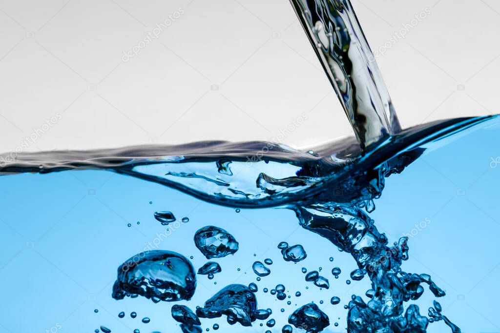Pouring blue water splash and air bubbles isolated on white background