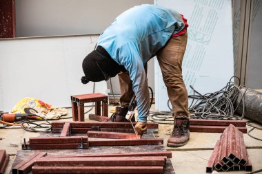 İnşaat alanında metal kaynak yaparken korunmak için kar maskesi ve güneş gözlüğü takan bir işçi.