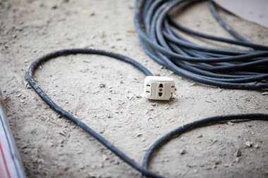 İnşaat alanında yerde eski elektrik prizi soketi ve kablo.