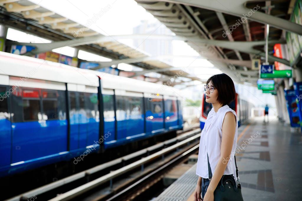 Asian young short hair woman waiting for arriving train on platform