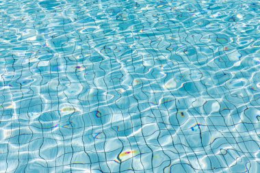 Yüzme havuzunun berrak ve parlak mavi sularında güneş yansıması, parlak mavi su dalgalanması arka plan, su dokusu, desen