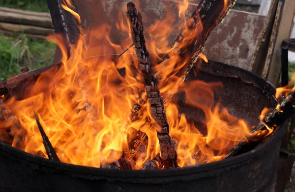 Wood burning in an iron barrel. Fire close-up. Charred boards