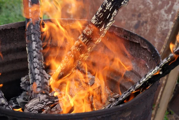 Wood burning in an iron barrel. Fire close-up. Charred boards