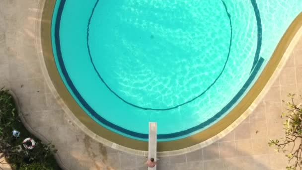 Νεαρός άνδρας πηδάει από το βατήρα στην εξωτερική πισίνα, κορυφαία θέα — Αρχείο Βίντεο