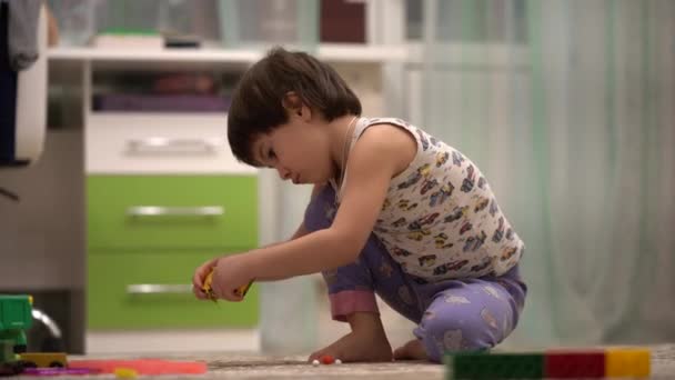 Niño jugando con un coche de juguete en su habitación  . — Vídeos de Stock